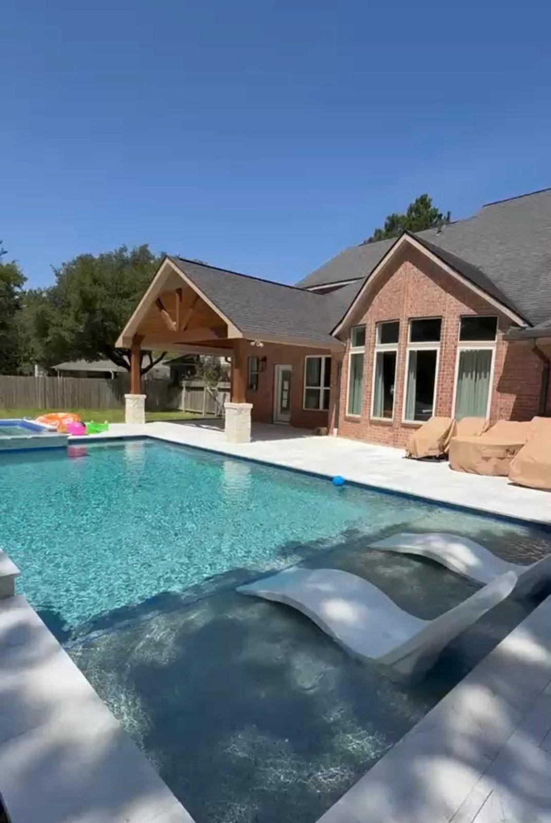 Poolside patio cover with gable roof and stone columns